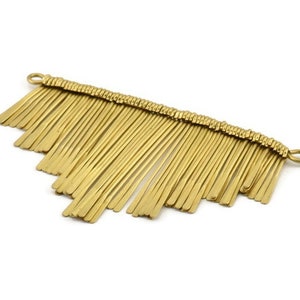 May include: Gold metal fringe trim with a straight edge and a loop at each end. The fringe is made of thin, flat strips of metal that are arranged in a cascading pattern.