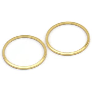 May include: Two gold-colored metal rings, one slightly larger than the other, are shown on a white background.