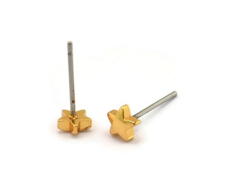 May include: Two gold-colored star-shaped stud earrings with silver posts. The earrings are small and have a simple, minimalist design. The studs are on a white background.