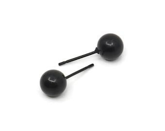 May include: A pair of black ball stud earrings. The earrings are made of metal and have a simple, classic design.