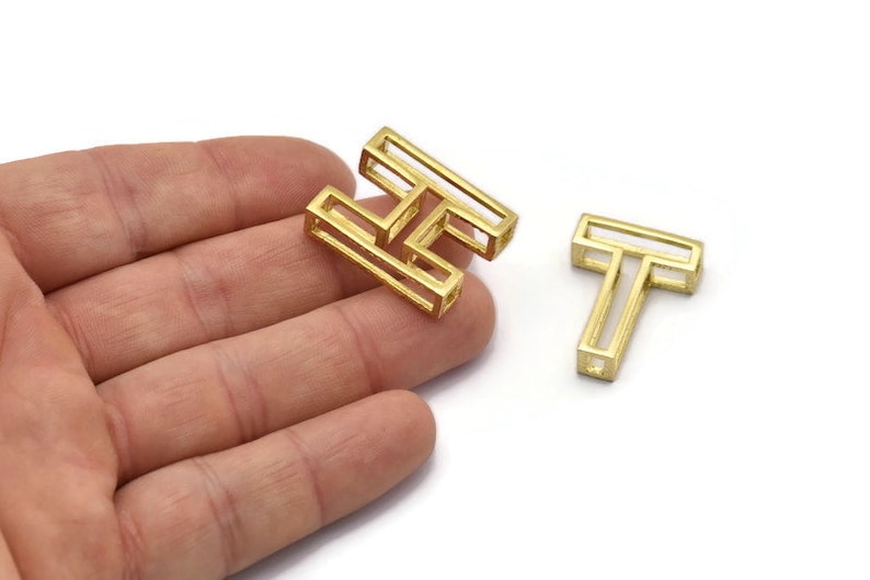 Pu&ograve; includere: Due ciondoli in metallo color oro, uno a forma della lettera H e l'altro a forma della lettera T. I ciondoli sono vuoti e hanno un design geometrico.