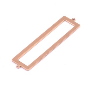 Peut inclure: Un cadre rectangulaire en or rose avec deux anneaux de saut en haut. Le cadre est ouvert sur tous les côtés et est parfait pour ajouter une touche personnelle aux bijoux.