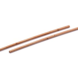 Puede incluir: Dos tubos de cobre, cada uno de aproximadamente 30 cm de largo, est&aacute;n paralelos entre s&iacute; sobre una superficie blanca.