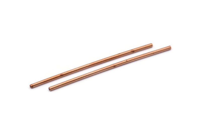 Puede incluir: Dos tubos de cobre, cada uno de aproximadamente 30 cm de largo, est&aacute;n paralelos entre s&iacute; sobre una superficie blanca.
