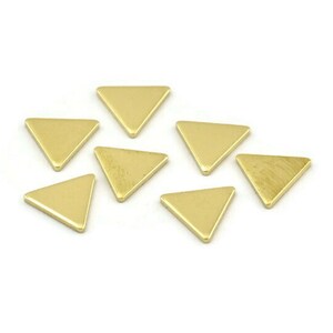 Peut inclure: Huit breloques en métal de forme triangulaire de couleur dorée. Les breloques sont petites et plates, avec une surface lisse et polie.