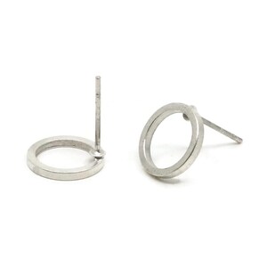 May include: Two silver-colored, open-circle stud earrings. Each earring features a circular design with a post for insertion into the ear. The earrings are displayed against a white background.