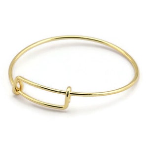 May include: A gold-toned bangle bracelet with a simple, rectangular clasp.