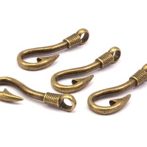 Op de afbeelding: Vier antieke goudkleurige metalen haken met een vishaakontwerp. De haken zijn allemaal even groot en even gevormd en zijn in een rij gerangschikt.