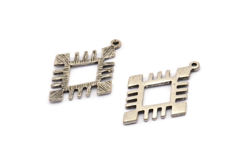 May include: Two silver metal charms in the shape of a square with an inner square. The charms have a textured design and a loop at the top for attaching to jewelry.