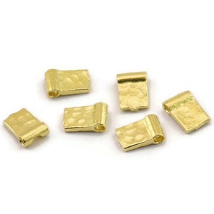 Può includere: Sei tappi per perline in metallo color oro con una texture martellata. I tappi sono di forma rettangolare con un piccolo foro nella parte superiore.