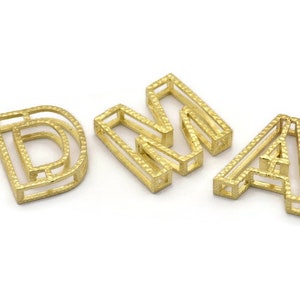 Pu&ograve; includere: Lettere in metallo color oro che compongono la parola "DNA". Ogni lettera &egrave; composta da pi&ugrave; strati di metallo, creando un effetto tridimensionale.