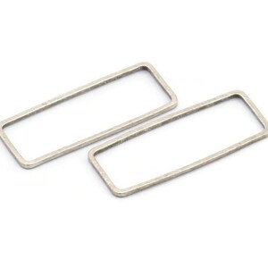 Può includere: Due orecchini a cerchio rettangolari in argento. Gli orecchini sono semplici e minimalisti.