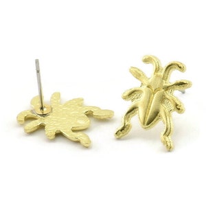 May include: A pair of gold-toned earrings featuring a detailed spider design. The earrings are stud style with a post and butterfly backing.