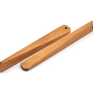 May include: Two wooden chopsticks, one is slightly longer than the other, both are light brown in color.