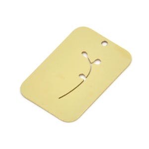 Può includere: Un'etichetta in metallo dorata con un piccolo design floreale delicato tagliato al centro.