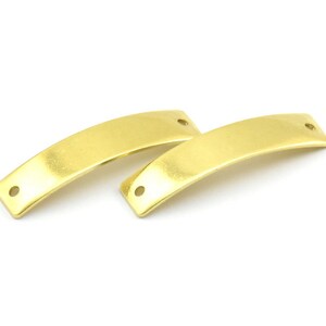 Pode incluir: Dois conectores de barra de metal de cor dourada com bordas arredondadas e dois furos cada.