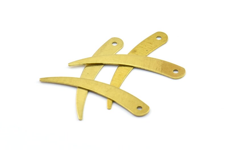 May include: Four brass, curved, metal pieces with holes. The pieces are arranged in a criss-cross pattern.