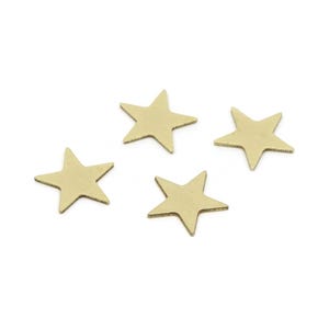 May include: Four small, flat, five-pointed star-shaped cutouts made of a smooth, matte gold-toned metal. Each star features sharp, defined points and a uniform, solid metallic surface, arranged in a loose, scattered formation.