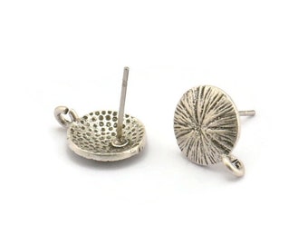 May include: A pair of silver-toned earring blanks with a textured circular design. Each blank has a post and a loop for attaching a charm or pendant.