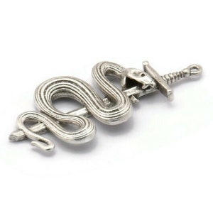May include: A silver pendant featuring a snake wrapped around a sword. The snake's head is open, as if biting the sword.