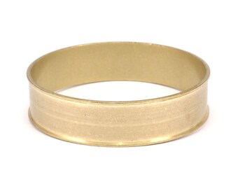 May include: A gold-colored metal ring with a wide band and a smooth, slightly textured surface.