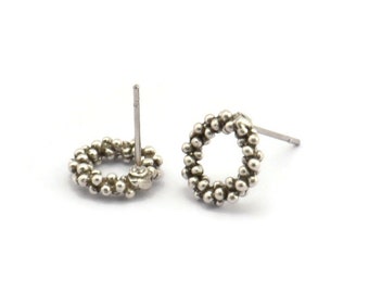 May include: A pair of silver stud earrings with a circular design made of small beads.