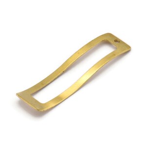 Pode incluir: Um marcador de página de metal dourado com um recorte retangular no centro. O marcador de página é ligeiramente curvado e tem um pequeno furo na parte superior.