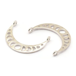 Peut inclure: Deux breloques en forme de croissant de lune argentées avec un motif découpé des phases de la lune. Les breloques ont une boucle en haut pour les attacher à des bijoux.