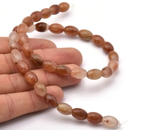 Puede incluir: Una hebra de cuentas de piedras preciosas ovaladas, translúcidas, de color marrón claro con un tono marrón rojizo. Las cuentas están enhebradas en un hilo transparente.
