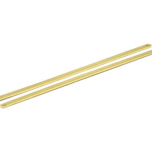 May include: Two gold metal rods with rounded ends. The rods are parallel to each other and are approximately 25 cm long.