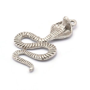 Può includere: Ciondolo in argento a forma di cobra con il cappuccio sollevato. Il ciondolo è dettagliato con squame e ha un anello per attaccarlo a un braccialetto o una collana.