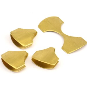 Puede incluir: Cuatro piezas de metal de color dorado, tres son peque&ntilde;as y de forma triangular con un borde redondeado, y una es m&aacute;s grande y tiene forma de ocho.