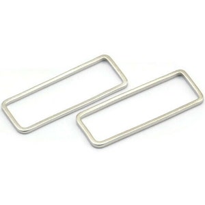 May include: Two silver rectangular hoops, each with a smooth, polished finish. The hoops are slightly different in size, with the larger hoop on top of the smaller hoop.
