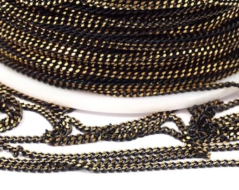 May include: A spool of black chain with gold accents. The chain is made of metal and has a curb link design.
