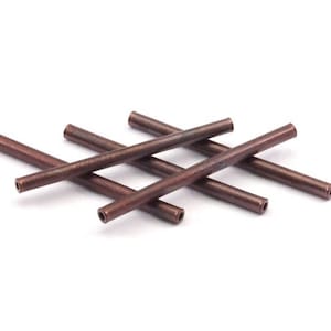 Peut inclure: Cinq tubes métalliques de couleur cuivre, chacun avec un centre creux, sont disposés en forme de croix. Les tubes mesurent environ 2,5 cm de long.