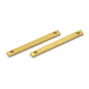 Puede incluir: Dos barras metálicas rectangulares de color dorado, con esquinas redondeadas y un agujero en cada extremo. Las barras están sobre una superficie blanca. Probablemente son hallazgos de joyería o componentes para la artesanía.