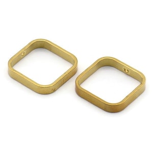 Op de afbeelding: Twee goudkleurige, vierkante metalen ringen met afgeronde hoeken. Elke ring heeft een klein gaatje aan één kant. De ringen worden op een witte achtergrond weergegeven.