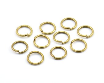 May include: Ten gold jump rings, also known as split rings, are arranged on a white background. These rings are commonly used in jewelry making and crafting.