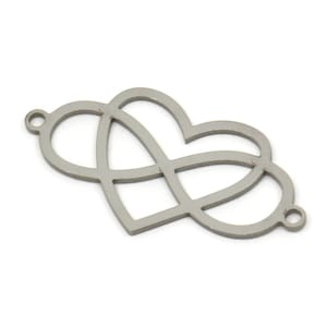 May include: Silver-toned metal charm featuring two intertwined hearts. The hearts are open and have a delicate, intricate design.