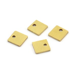 May include: Four gold square metal charms with a small hole in the center.