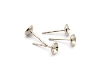 May include: Four silver-colored earring posts with flat, round tops and thin posts. The posts are scattered on a white background, showcasing their simple design and metallic sheen. These components are ideal for DIY jewelry making.