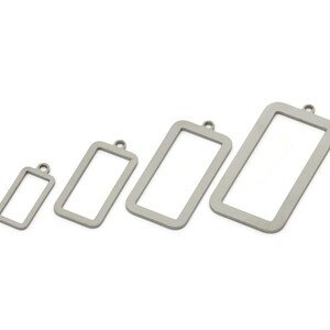 May include: Four silver-toned metal frames of different sizes, each with a loop at the top. The frames are arranged in a row from smallest to largest.