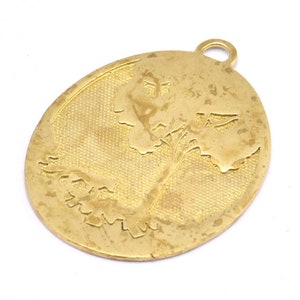 May include: Gold-toned oval pendant with a tree design. The pendant has a loop at the top for attaching a chain.