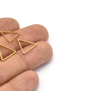 Puede incluir: Tres abalorios de metal de forma triangular de color dorado. Los abalorios est&aacute;n abiertos por un lado y tienen un acabado liso y pulido.