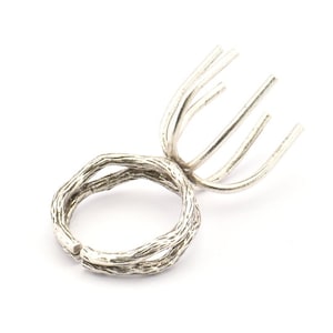 Puede incluir: Un anillo de plata con un diseño único que presenta una banda retorcida y una parte superior delicada y ramificada.