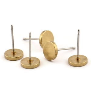 May include: Four gold-toned stud earrings with silver posts. The earrings are round and have a smooth, polished finish.