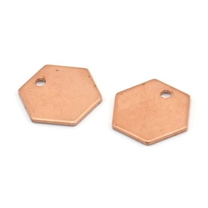 May include: Two rose gold hexagon shaped metal charms with a small hole in the center of each charm.