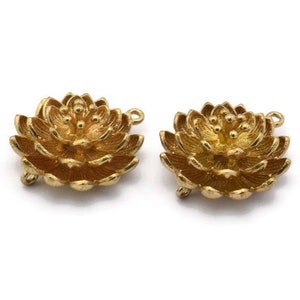 Peut inclure: Deux breloques en métal doré en forme de fleur avec une boucle de chaque côté. Les breloques sont détaillées avec un motif de fleur en relief.