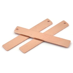 May include: Two rose gold metal bar pendants with a hole at the top. The bars are flat and rectangular.