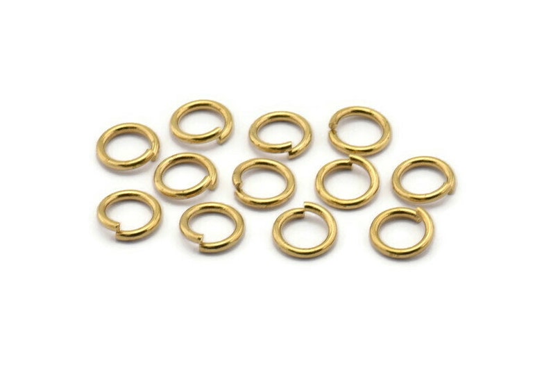 May include: A group of 12 gold jump rings, a type of jewelry finding used for connecting chains, cords, and other jewelry components.